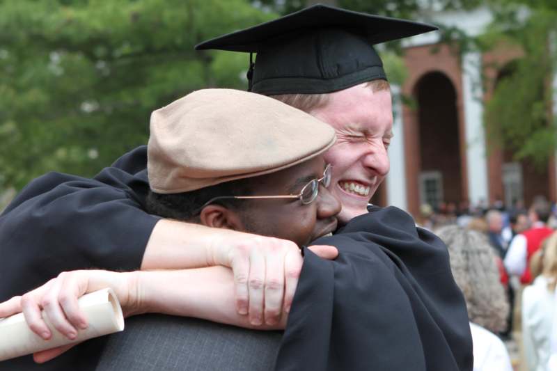 a man in a cap and gown hugging another man