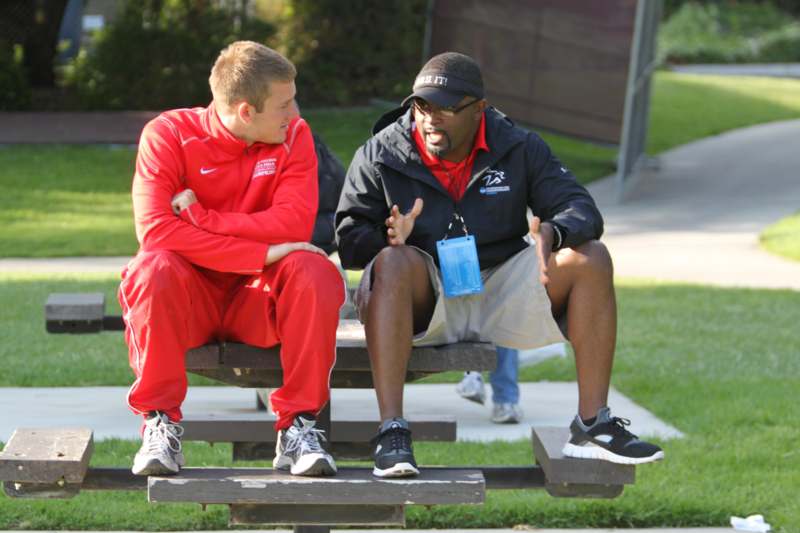 a man sitting on a bench talking to another man