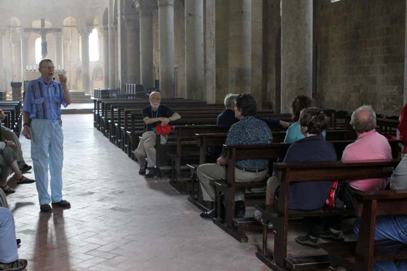 a man standing in a room with a group of people sitting in pews
