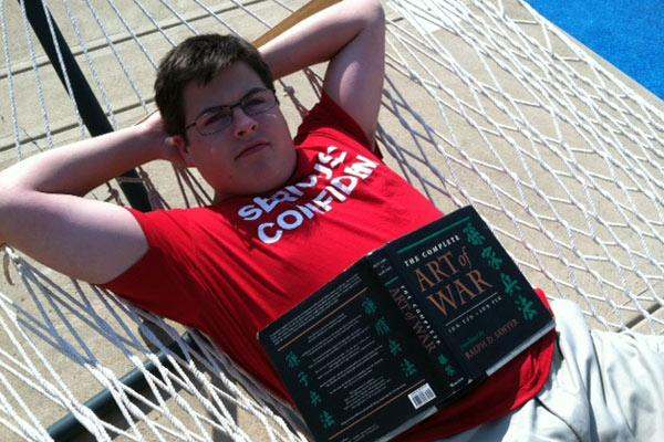a man lying in a hammock with a book