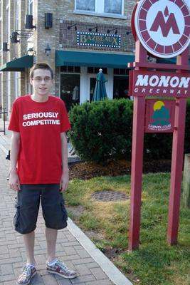 a young man standing in front of a sign