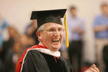 a man in a graduation gown laughing