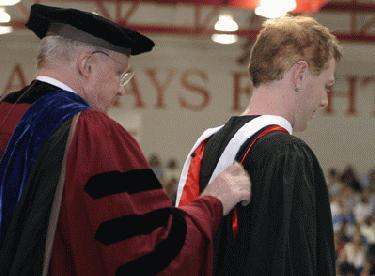 a man putting on a graduation gown