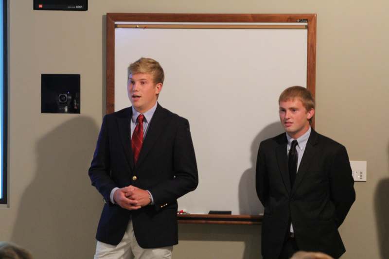 a group of men in suits standing in front of a whiteboard