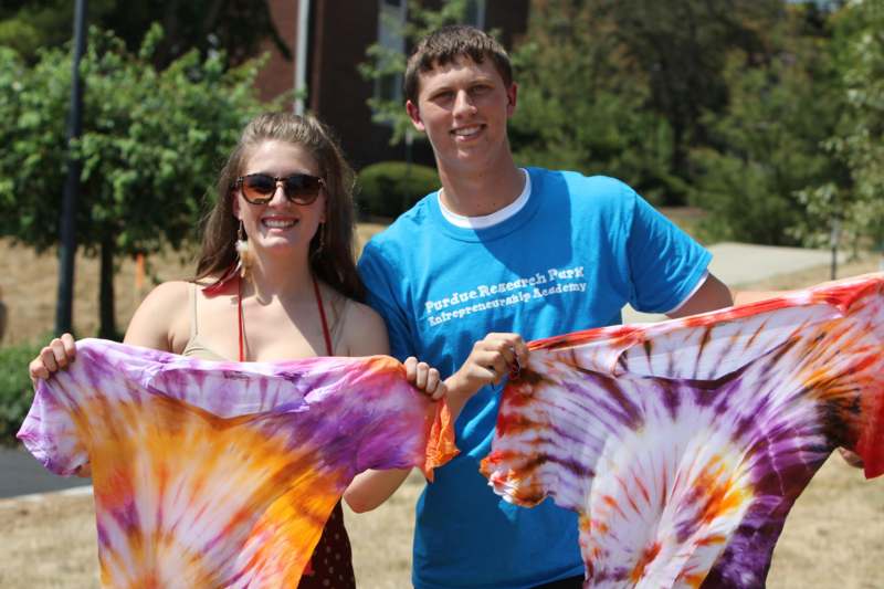 a man and woman holding up tie dye shirts