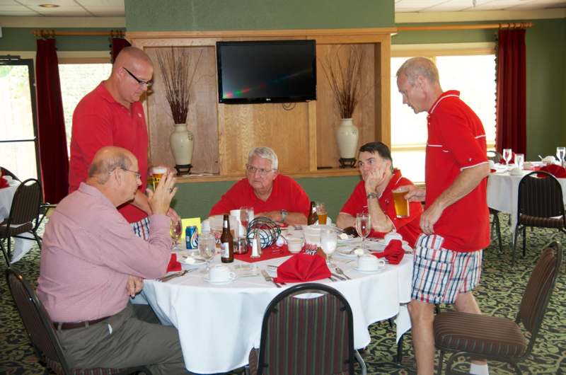 a group of men in red shirts at a table