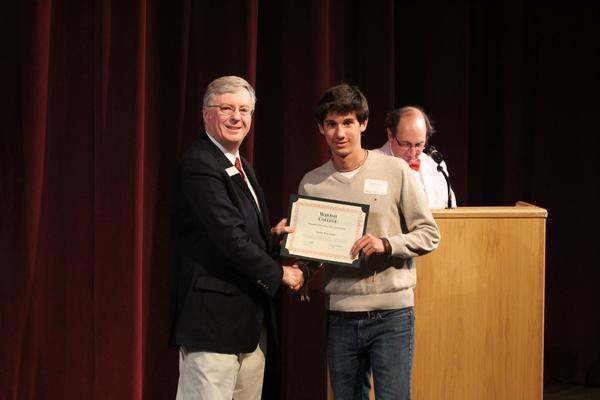 a man holding a certificate and receiving a man