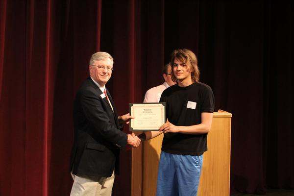 a man shaking hands with a man holding a certificate
