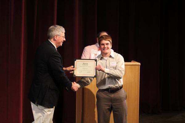 a man shaking hands with a man holding a certificate