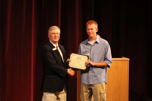 a man shaking hands with a man holding a certificate