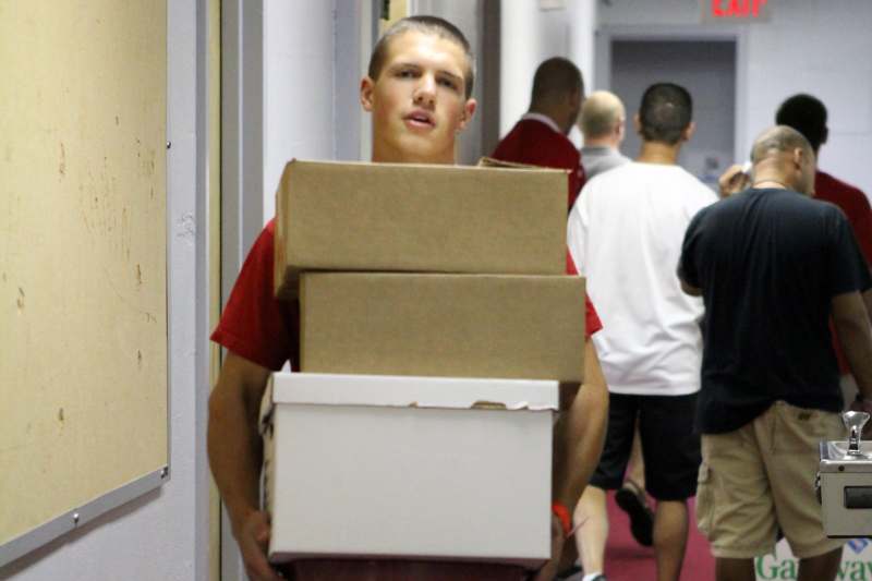 a man carrying boxes in a hallway