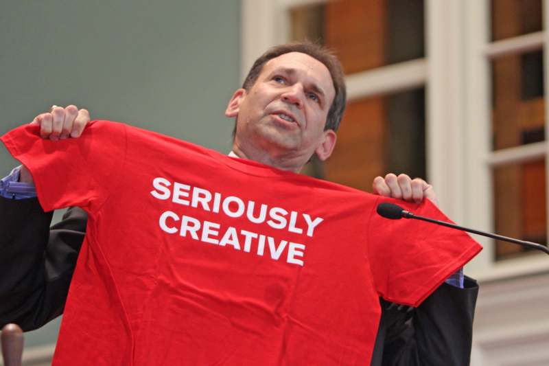 a man holding a red shirt with white text on it