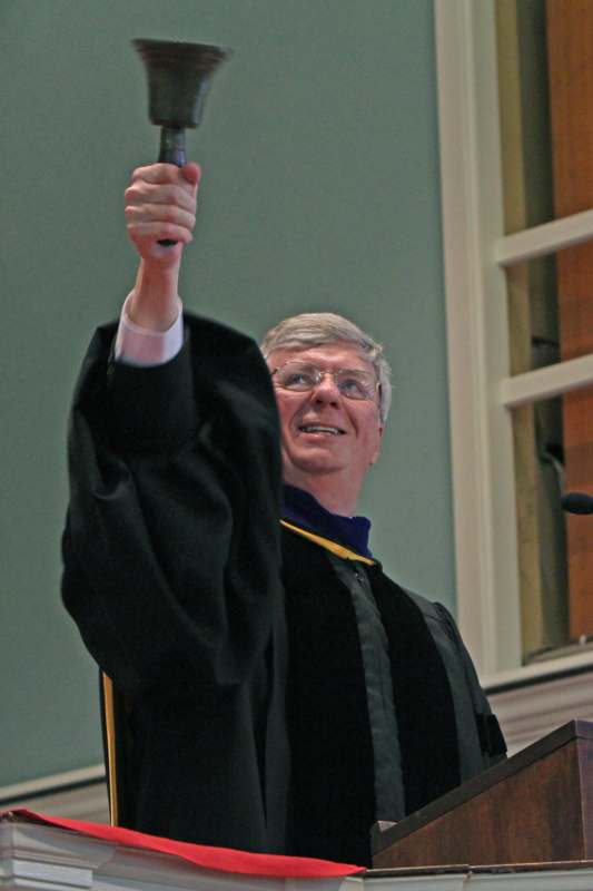 a man in a graduation gown holding up a microphone