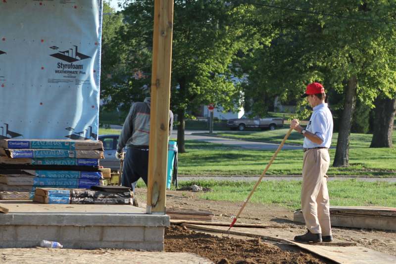 a man standing next to a pole with a shovel