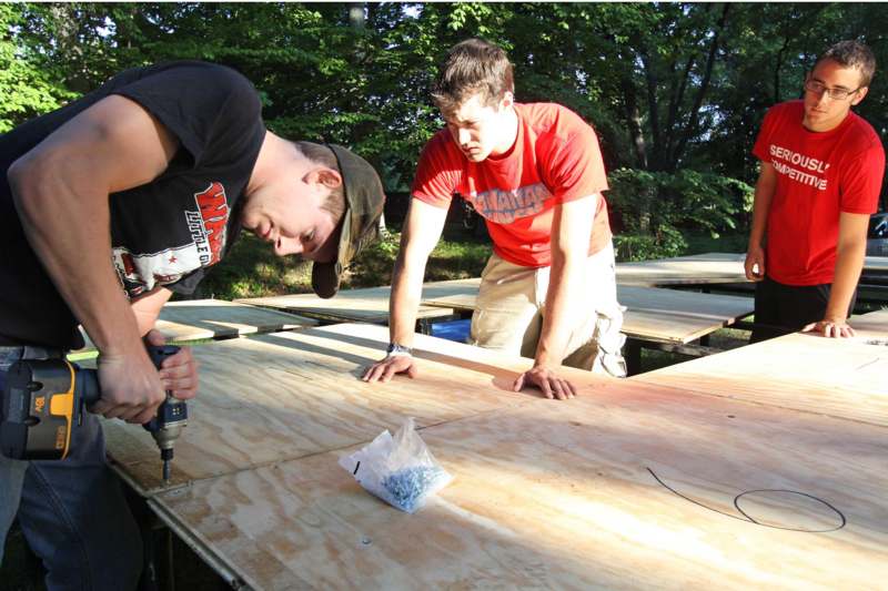 a couple of men working on a plywood table