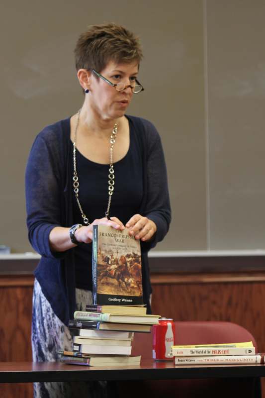 a woman standing next to a stack of books