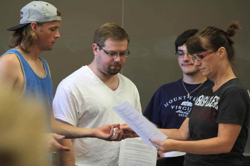 a group of people standing around a man holding a piece of paper
