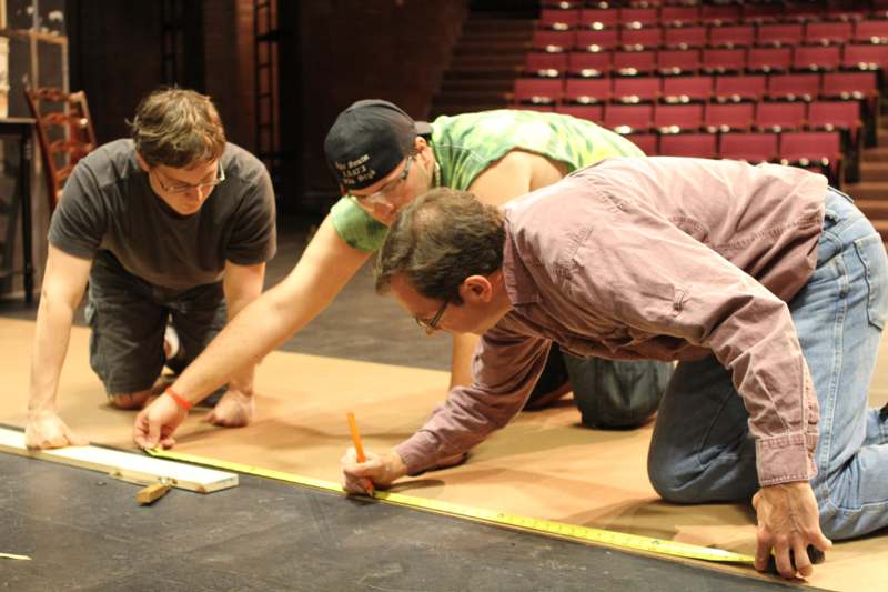 a group of men measuring a piece of wood