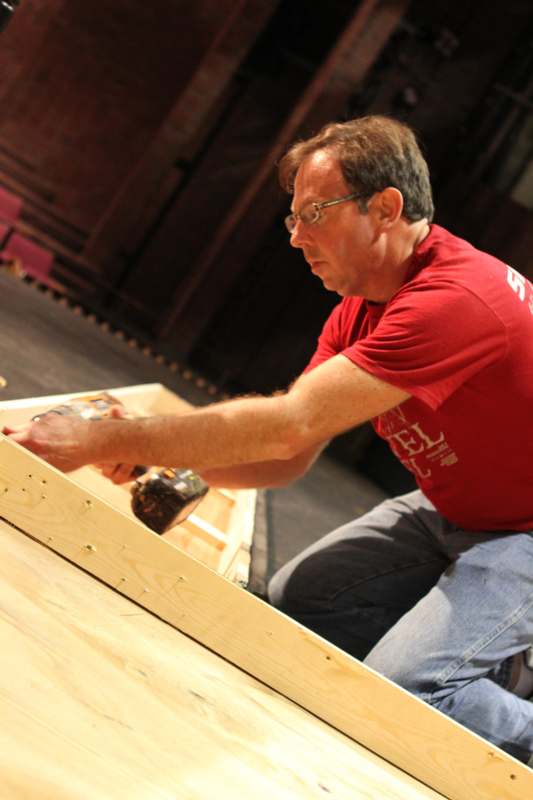 a man in a red shirt using a hammer to attach a wood box