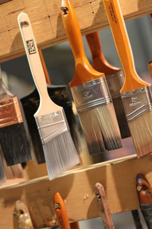 a group of paint brushes on a rack