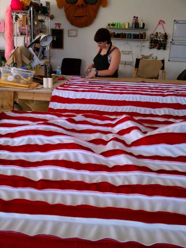 a woman sewing a red and white striped fabric
