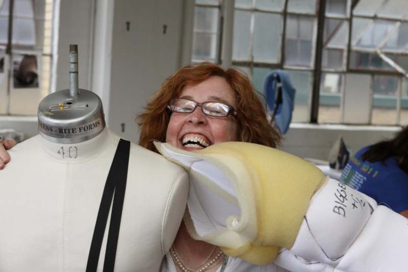 a woman smiling at a mannequin