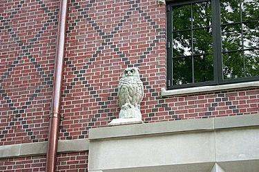a stone owl statue on a brick building