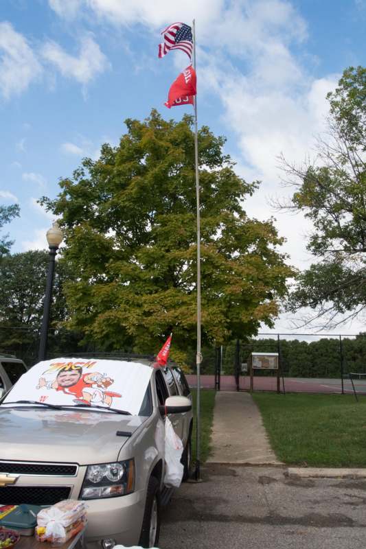 a car parked on the side of a road with a flag pole and trees