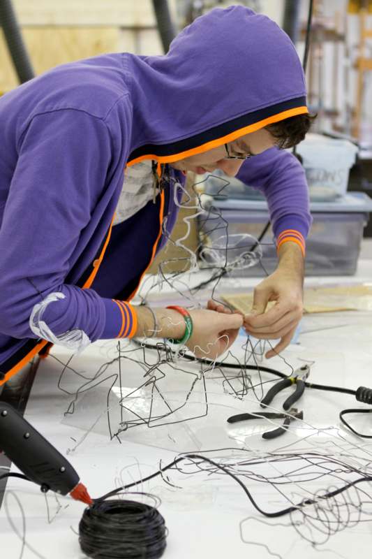 a man in a purple hoodie working on wires