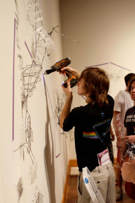 a group of people using a drill to make a drawing on a wall
