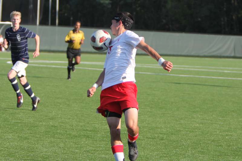 a man in a white shirt and red shorts kicking a football ball