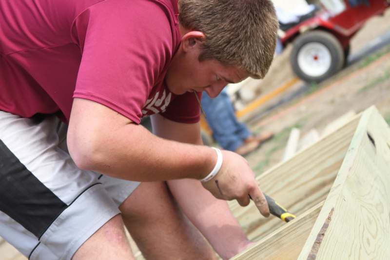 a man using a hammer to cut a wood plank