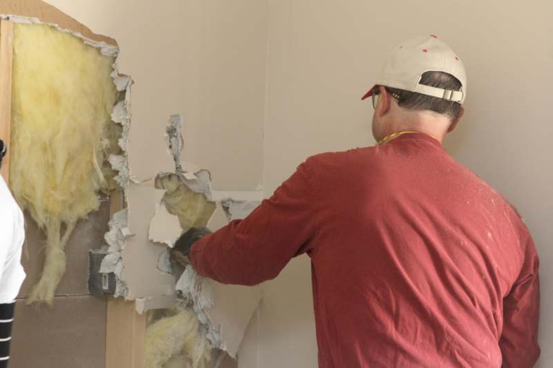 a man in a red shirt and white cap breaking a wall