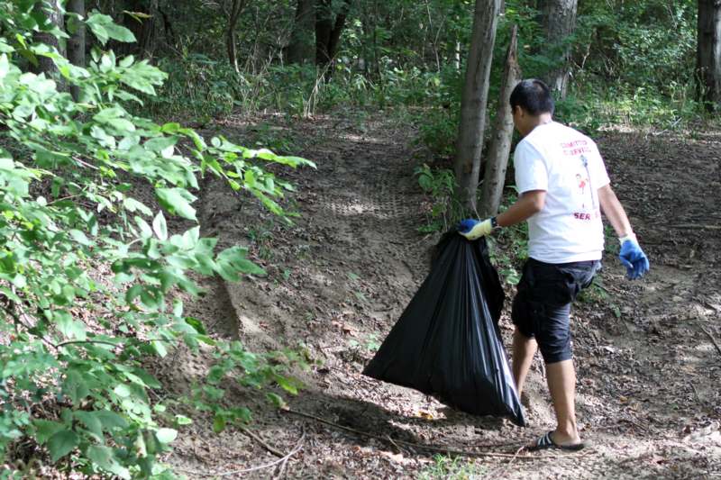 a man holding a black bag in the woods