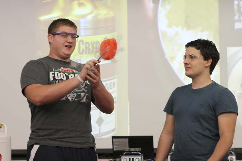 a man holding a red object with a person standing next to him