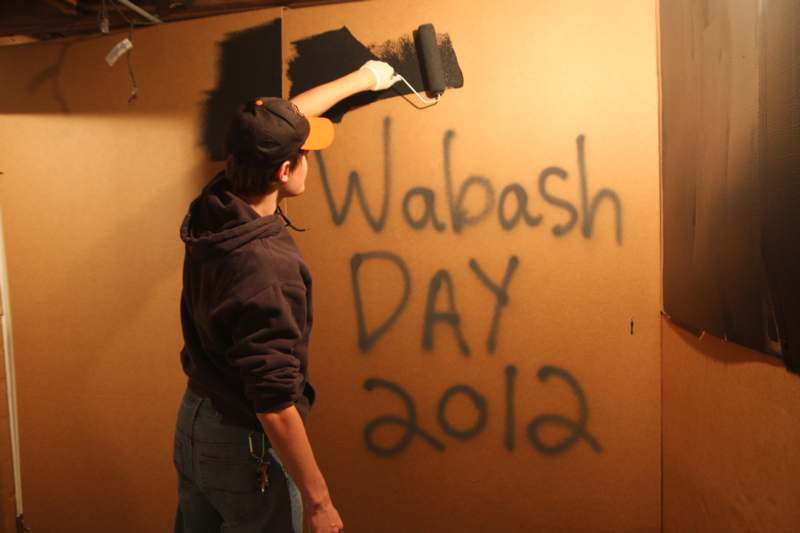 a man painting a wall with black paint