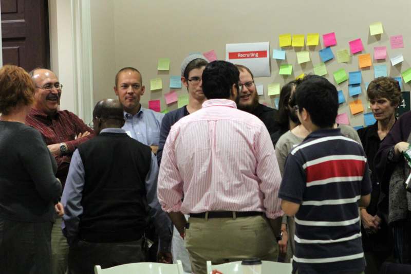 a group of people standing around a wall with post-it notes