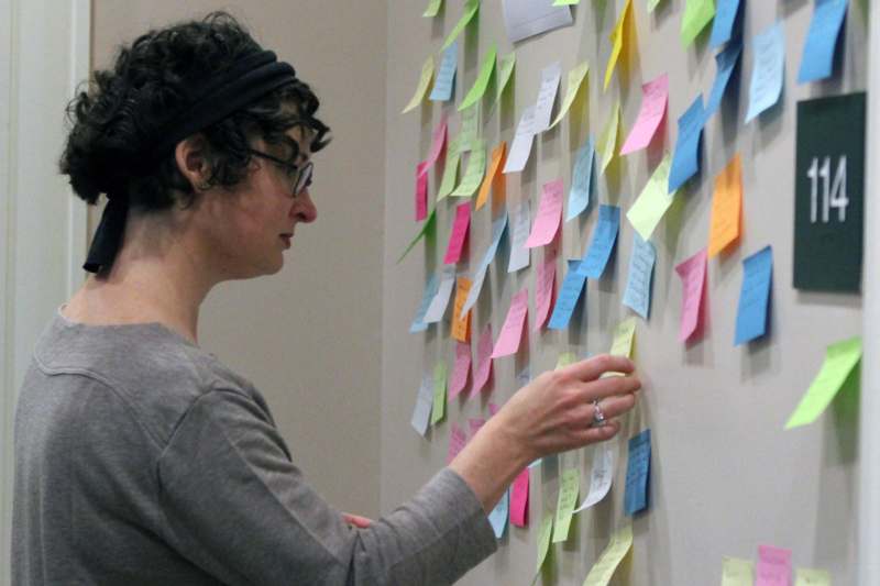 a woman looking at a wall with many sticky notes