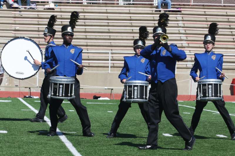 a group of people in blue uniforms playing instruments on a football field