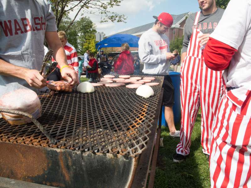 a group of people cooking burgers on a grill