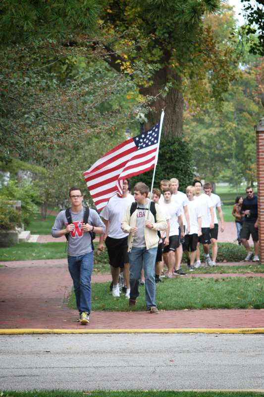 a group of people walking on a brick path with a flag