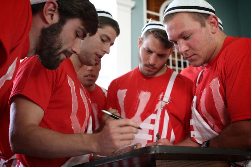 a group of men in red shirts and white hats looking at a pen