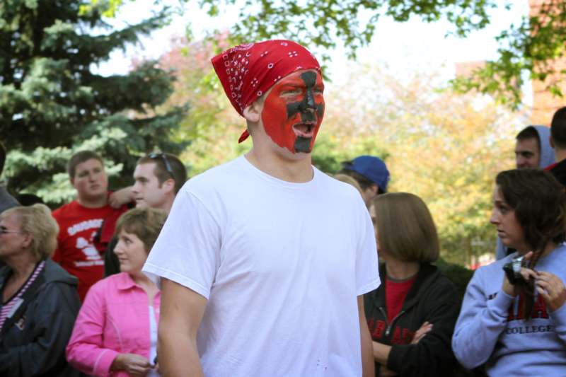 a man with face paint and red bandana standing in front of a crowd