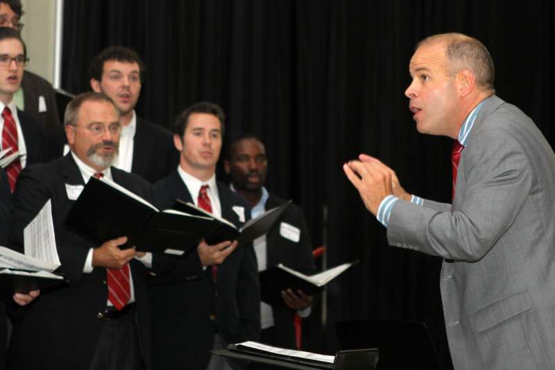 a man in a suit speaking to a group of men