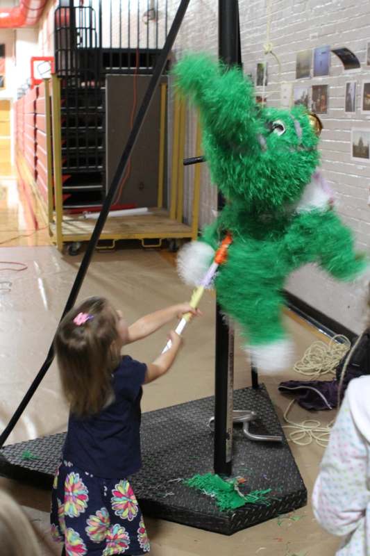a girl holding a stick in front of a green puppet