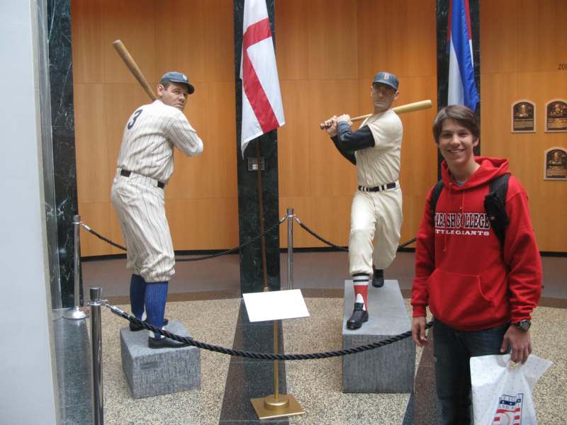 a man standing next to a statue of baseball players