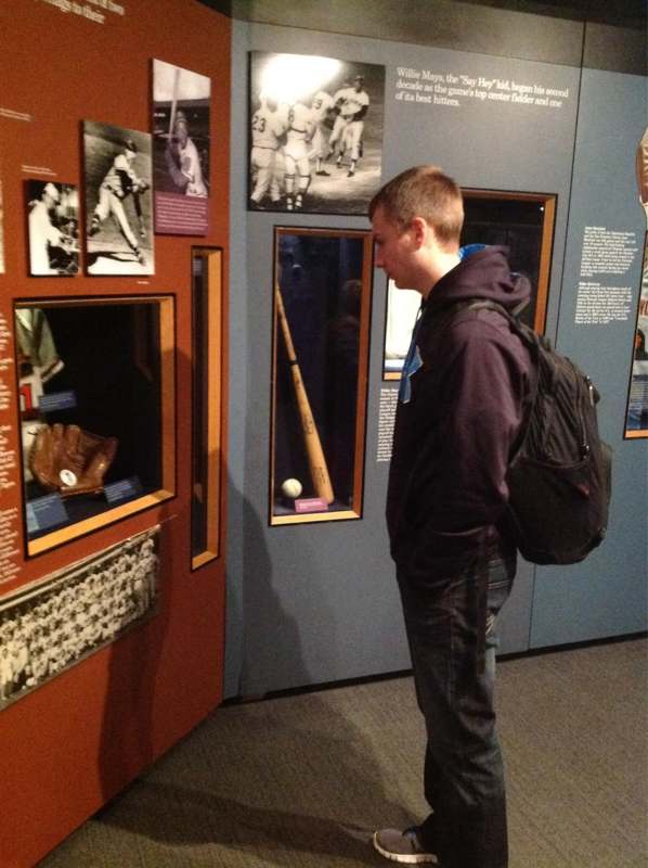 a man looking at a baseball bat in a display case