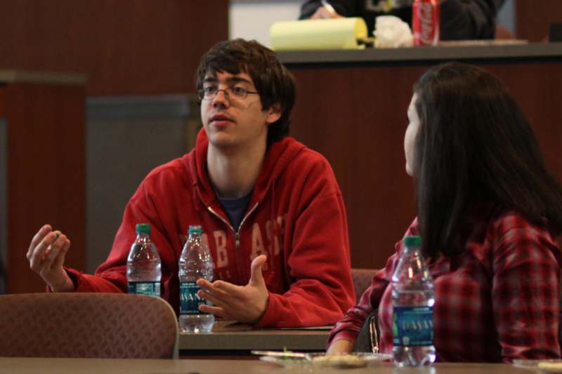 a man in red sweatshirt talking to a woman