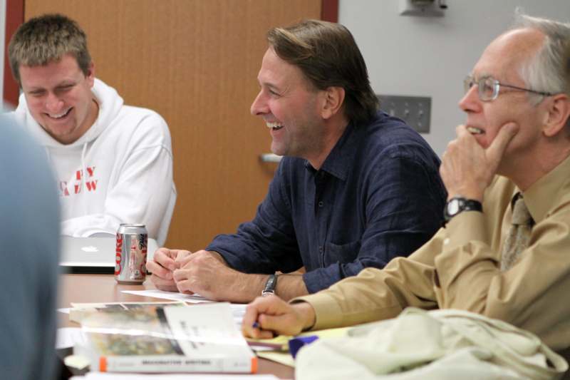a group of men sitting at a table laughing