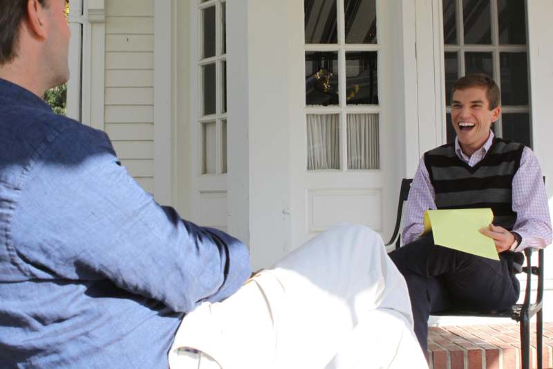 a man sitting on a porch with a yellow paper